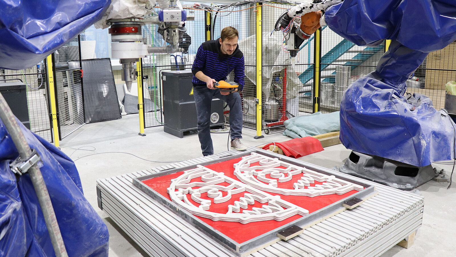 Enrico Rudolph vom Forschungsbereich "Leichtbau im Bauwesen" untersucht nach der Fertigung der Schwibbögen im Roboter-Komplex die Qualität des Schichtaufbaus des 3D-Betondrucks. Foto: Susanne Viertel